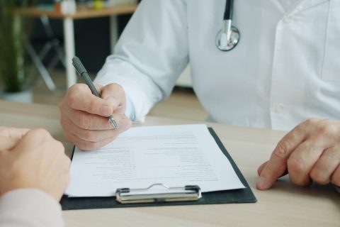 Médico anotando informações durante consulta com paciente