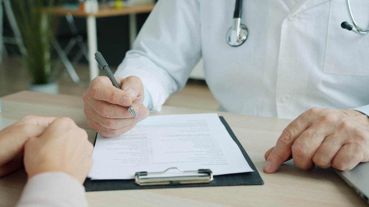 Médico anotando informações durante consulta com paciente
